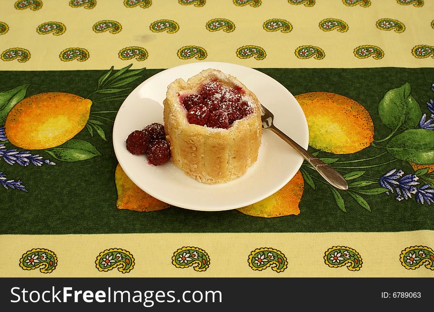 A French Raspberry Tart on a colorful tablecloth background.