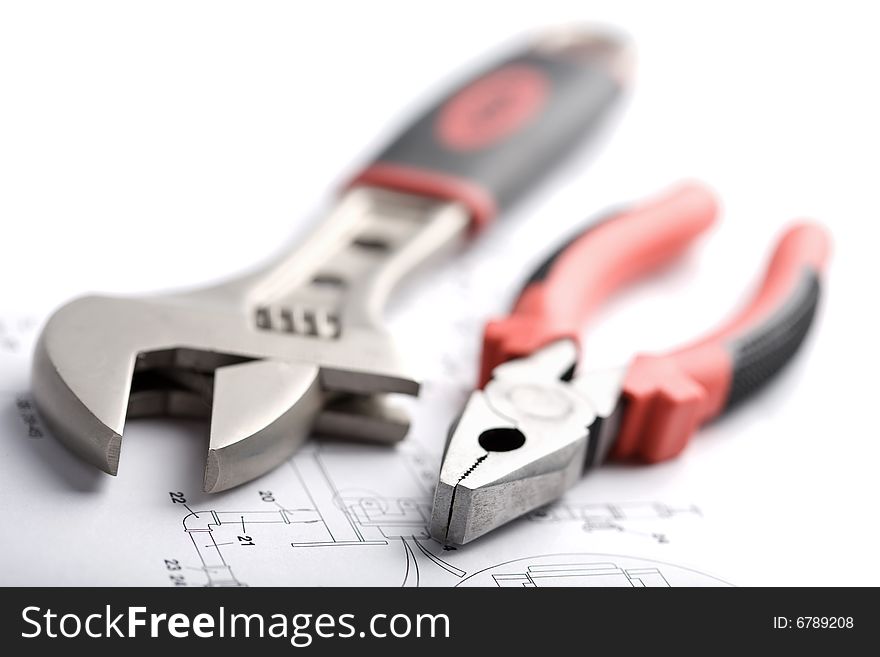 Wrench and pliers over technical drawing isolated on white