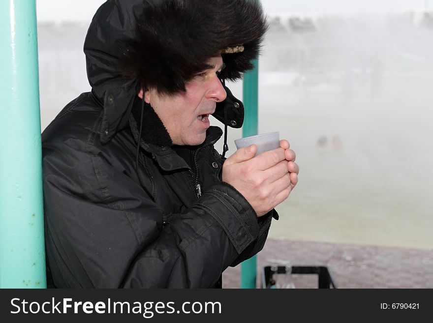 The man drinks a hot tea in winter. The man drinks a hot tea in winter