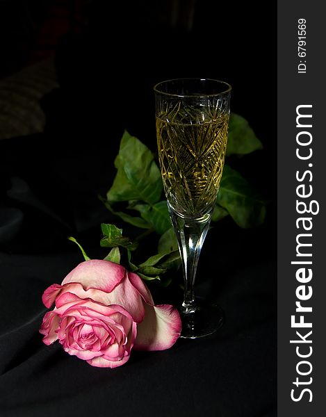 Glass with champagne and rose on black background