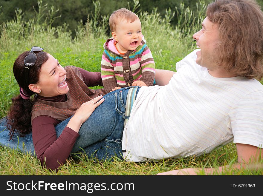 Parents with baby lies on nature, summer