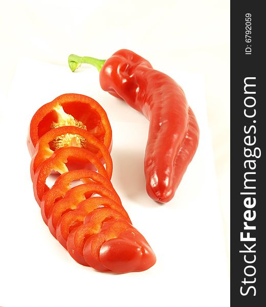 A food composition of chili and a red sliced pepper on isolated white background. A food composition of chili and a red sliced pepper on isolated white background