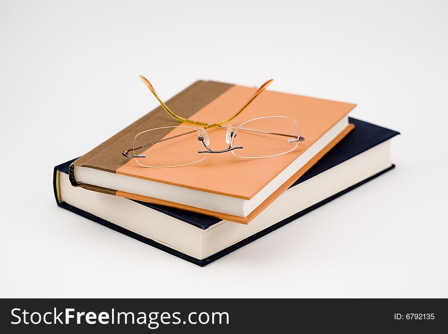 Two closed books and a pair of glasses