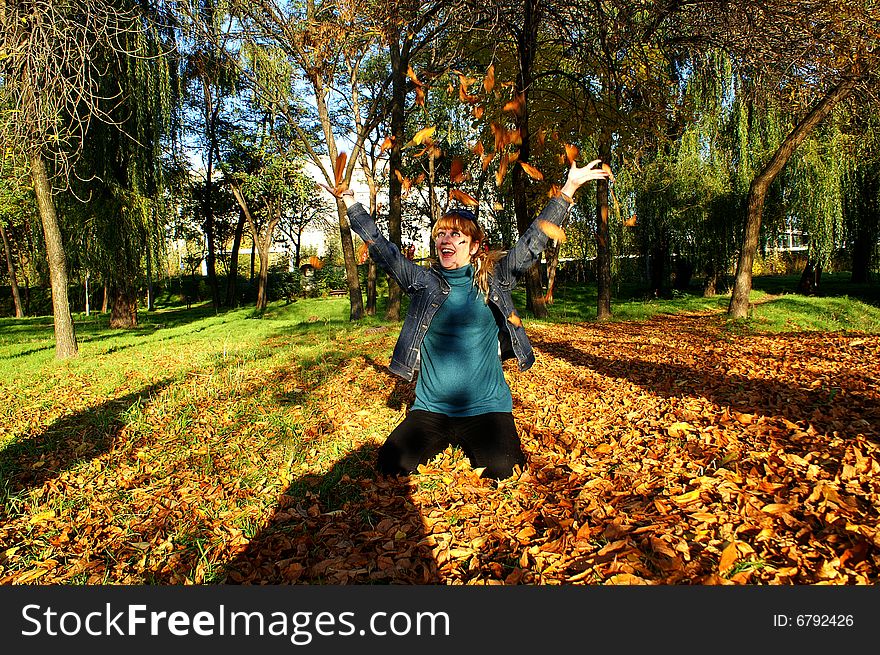 Laughing girl in autumn leaves looks happy