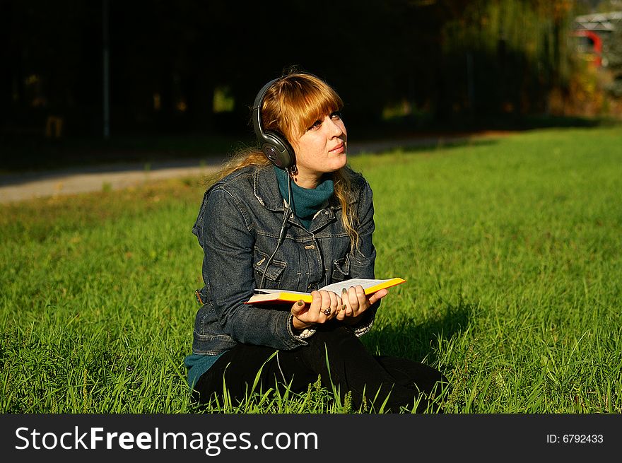 Girl with headphones reading the book. Girl with headphones reading the book