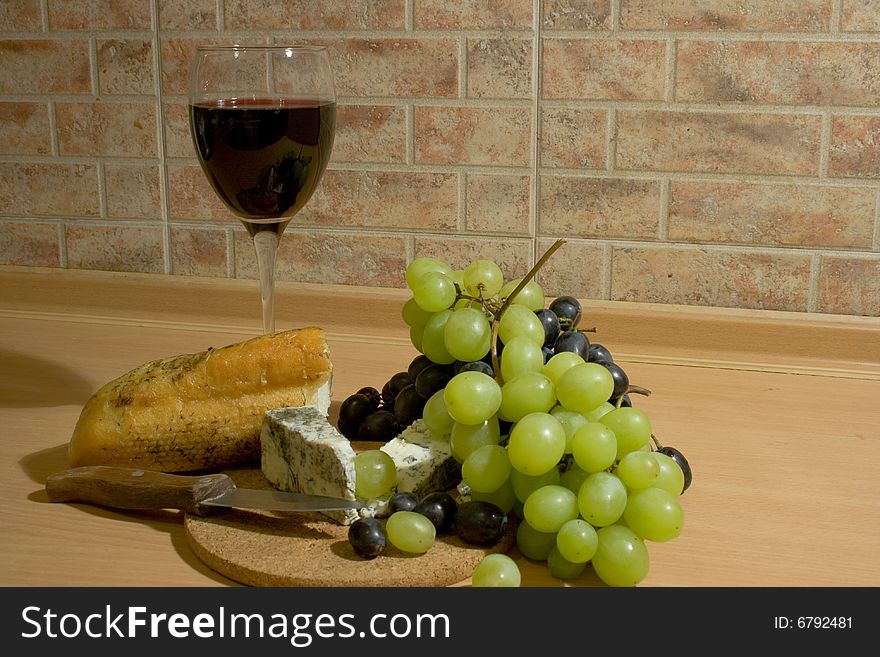 A glass of red wine with cheese, bread and grapes. A glass of red wine with cheese, bread and grapes