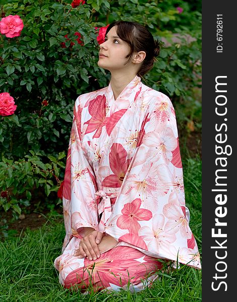 Girl in a pink yukata near rosebush. Girl in a pink yukata near rosebush