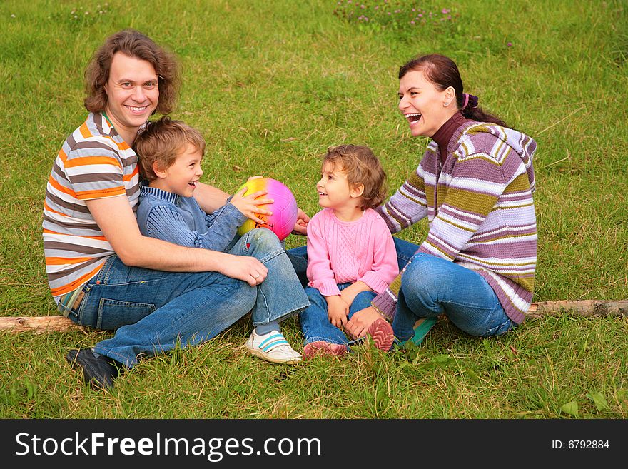 Family of four sits on grass