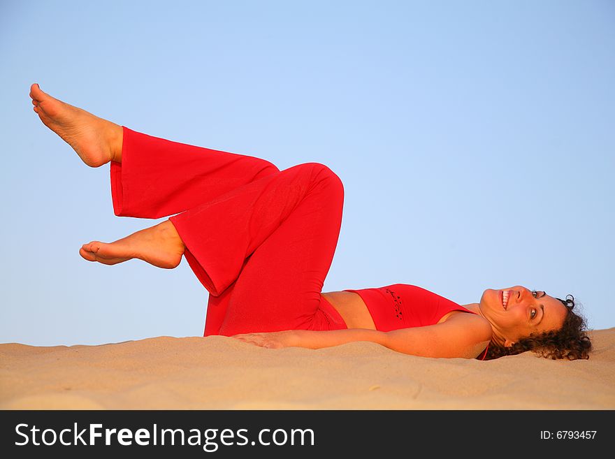 Young woman in red lies on sand, summer