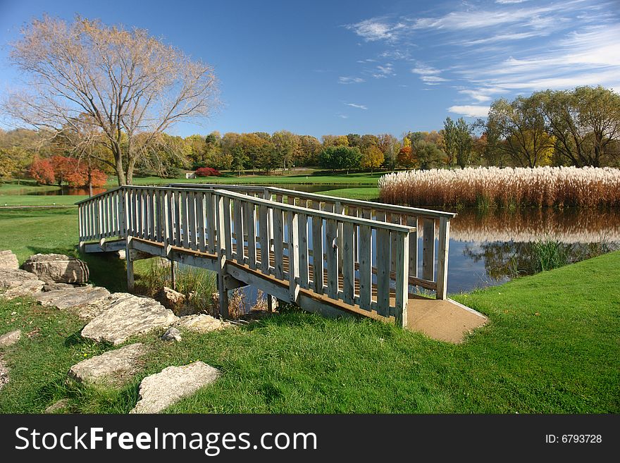 A picture of a small footbridge over pond in rural country