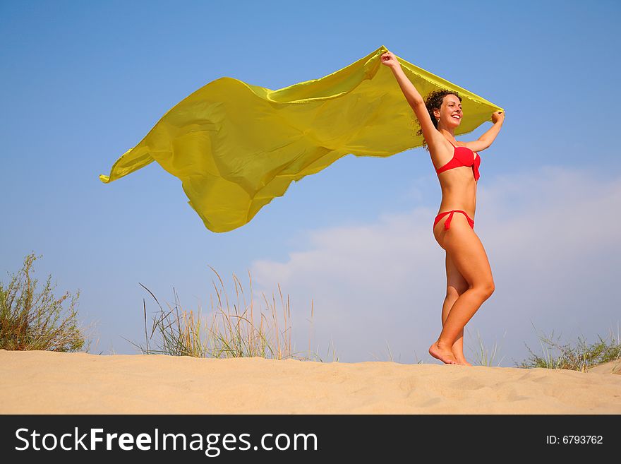 Young Girl On Sand With Yellow Shawl In Hands