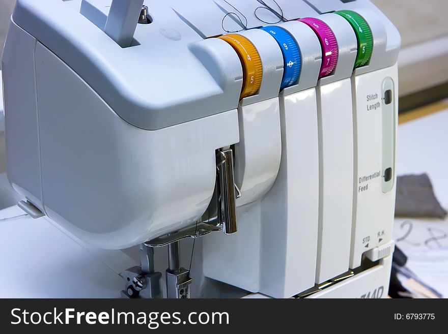 A part of a sewing machine with multicolor levers standing on the table