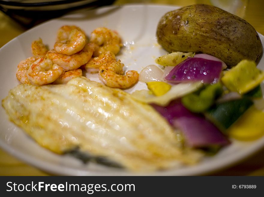 A delicious sea food platter with broiled vegetables and oven baked potato.