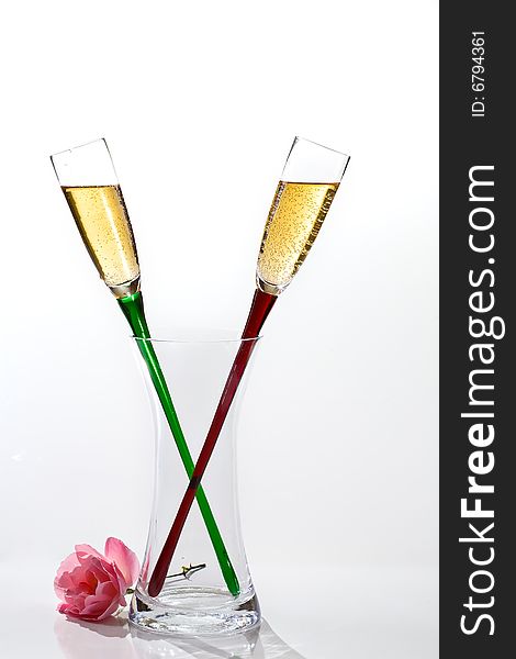 Two flutes of champagne and rose on white background