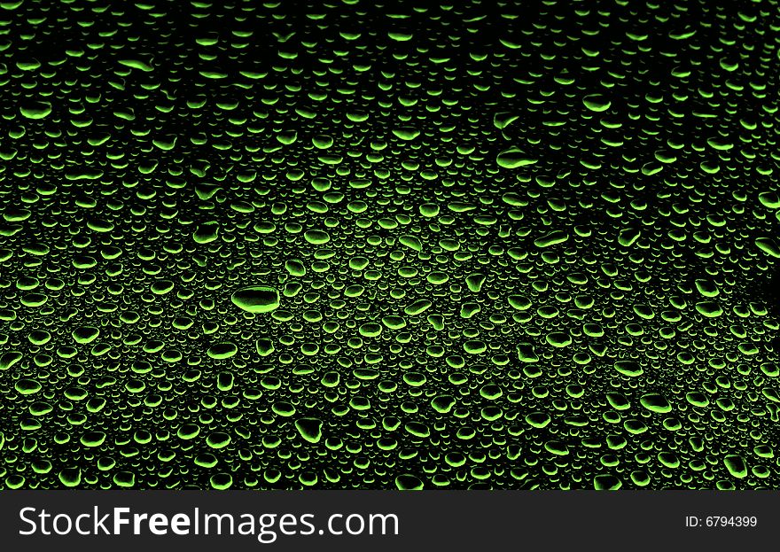 An abstract picture of green water drops on black