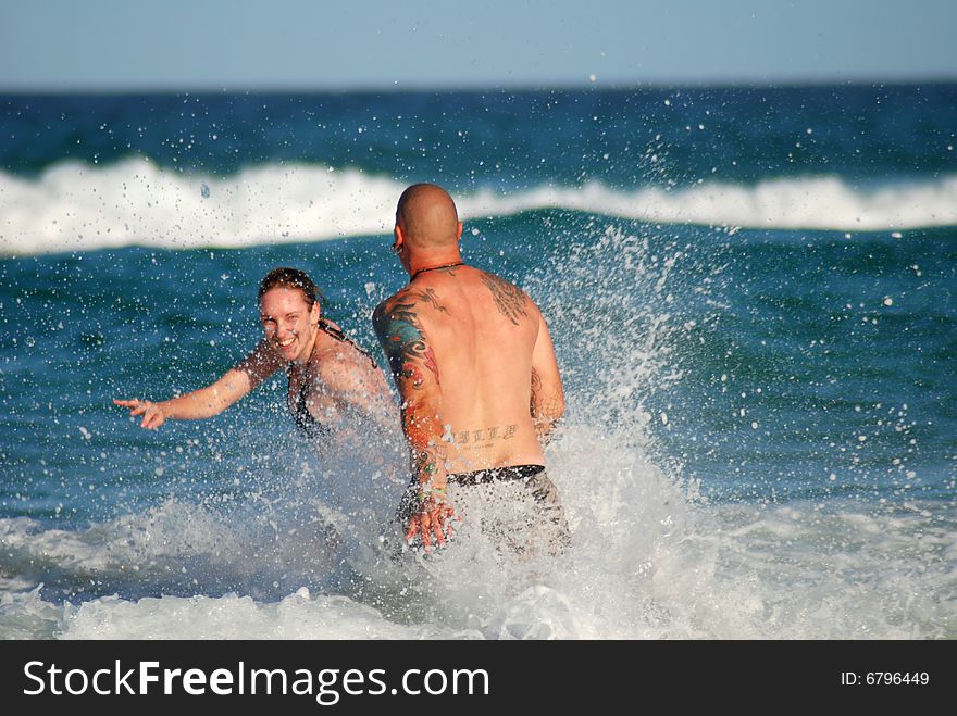 A young couple play in the surf. A young couple play in the surf