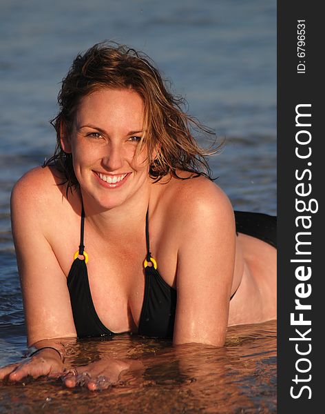 A beautiful young woman poses in shallows at the beach. A beautiful young woman poses in shallows at the beach