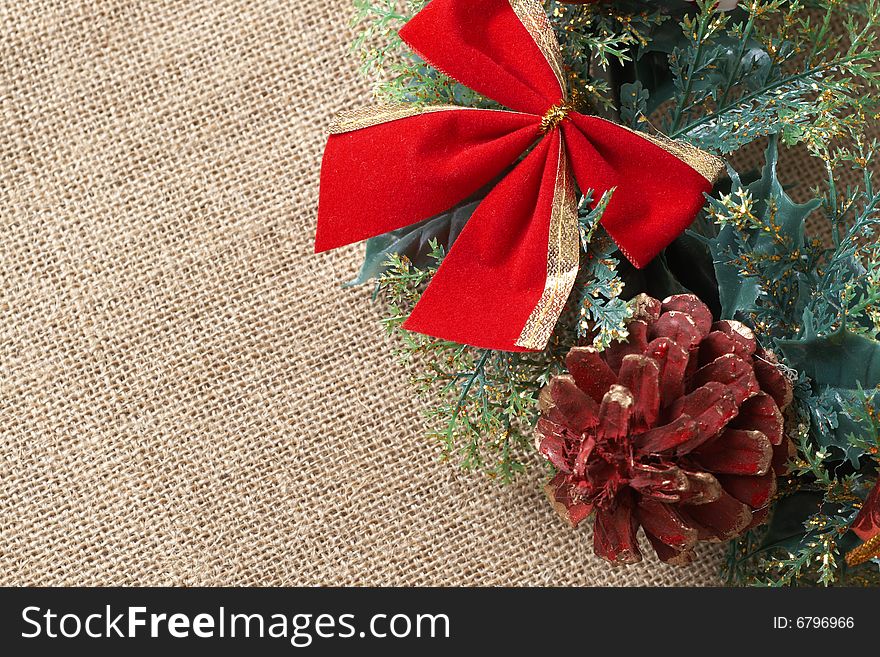 Christmas decoration with bow, leaves and cone on material background with copy space