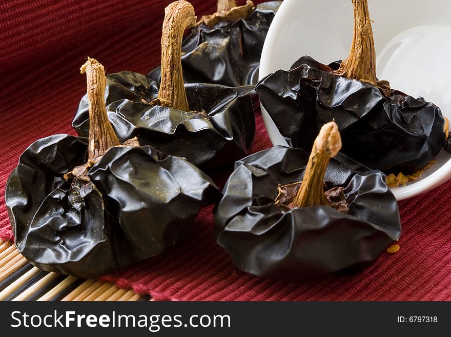 Black dried bell pepper on red background