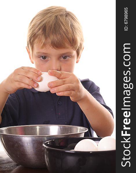 Little boy breaking an egg isolated on white