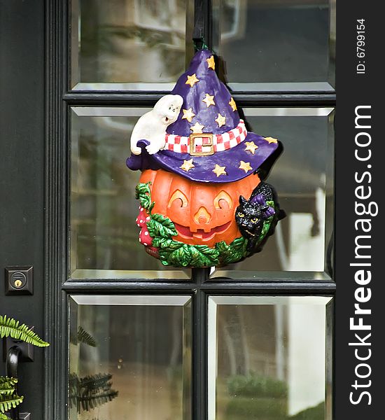 A Pumpkin wreath topped with a hat and surrounded by a ghost and a cat. A Pumpkin wreath topped with a hat and surrounded by a ghost and a cat