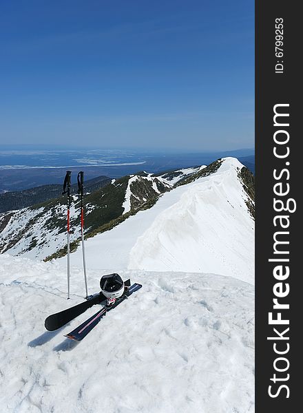 A pair of skis and helmet on the top of snowy mountain