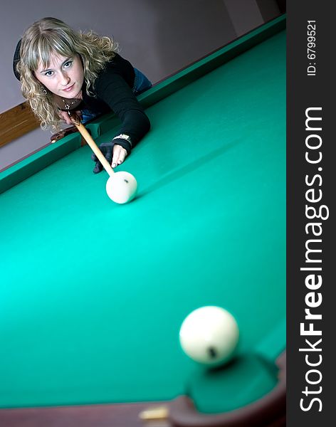 The girl beat the ball into a billiard pocket. The girl beat the ball into a billiard pocket