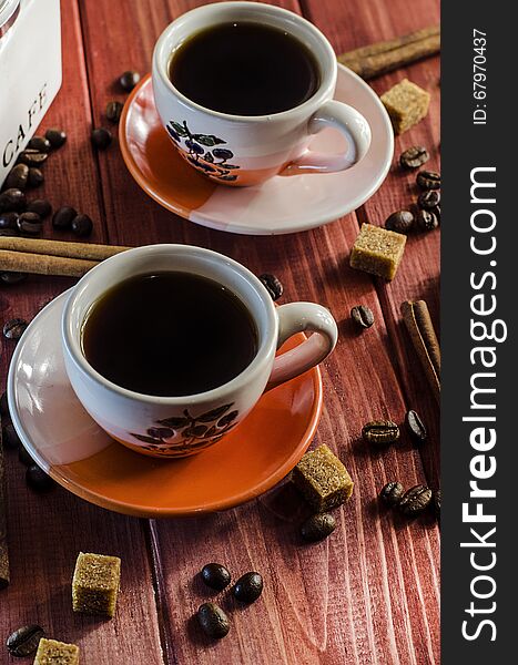 Brewed coffee and coffee beans with cinnamon on wooden background