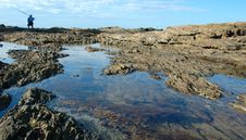 Man With Fishing Pole On Rocks Stock Image
