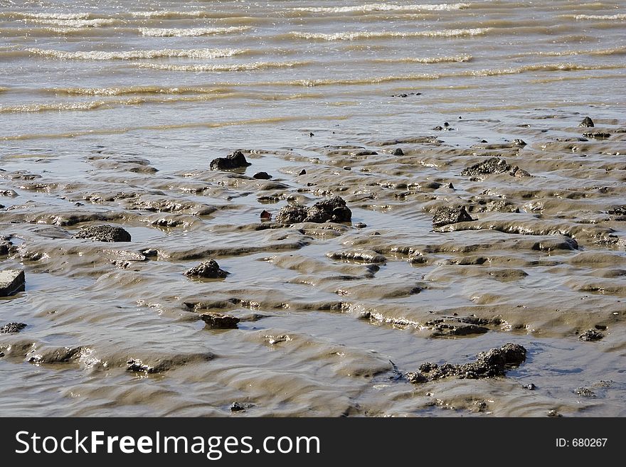 Wet sand stones at the ege of the shore, with small waves in the background. Wet sand stones at the ege of the shore, with small waves in the background.