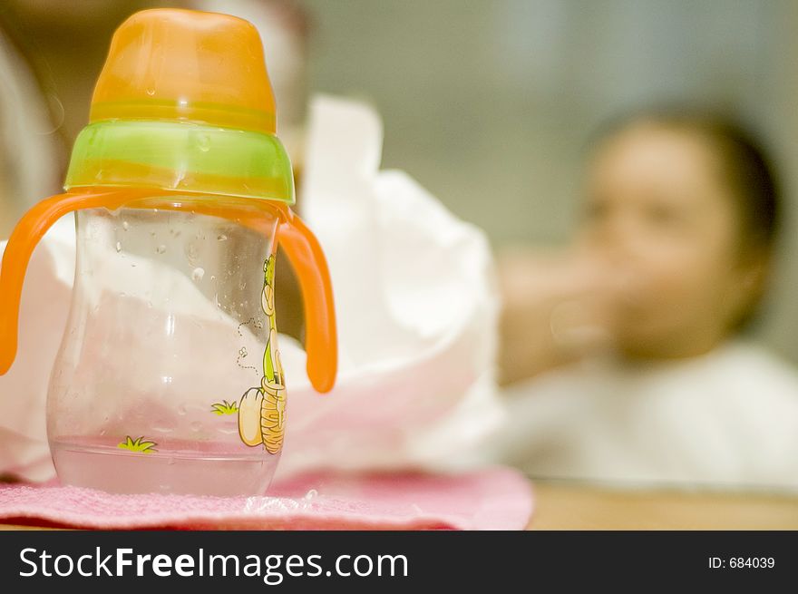 Baby bottle with wather and out of focus baby in background. Baby bottle with wather and out of focus baby in background