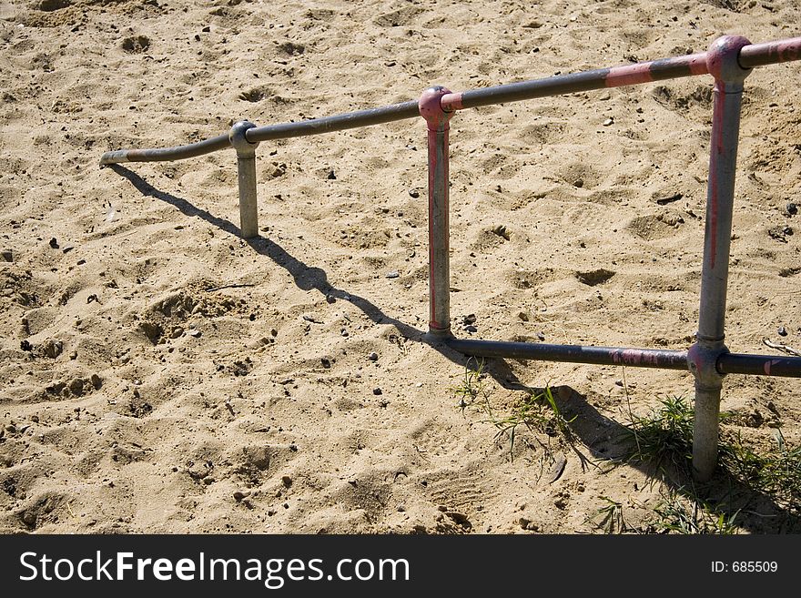 A metal hand rail disappering into the sand. A metal hand rail disappering into the sand.