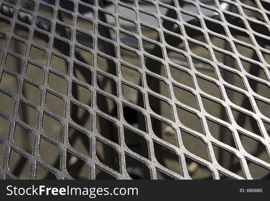 A close up of a metal grid garden table top, looking through to table base. A close up of a metal grid garden table top, looking through to table base.