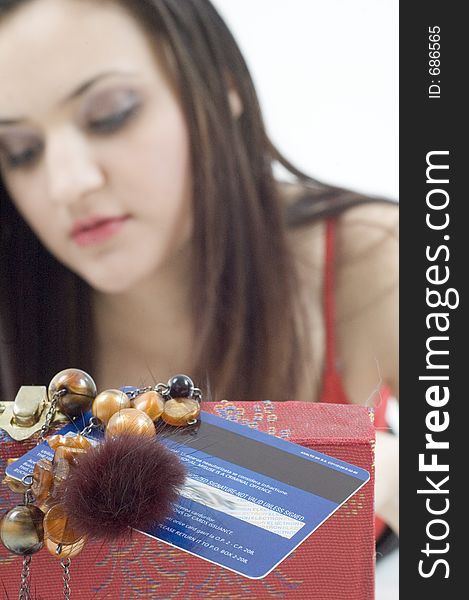 Young woman looking in her jewelery box with a credit card on the cover. Young woman looking in her jewelery box with a credit card on the cover