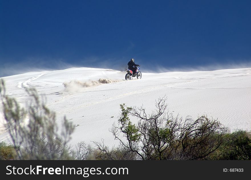 Trailbike Rider climbs dune. Trailbike Rider climbs dune
