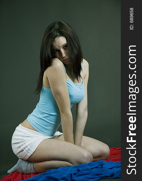 Young pretty brunette poses in the studio, dressed casual, with a light blue top and mini skirt, trying various expressions, over a dark background. Young pretty brunette poses in the studio, dressed casual, with a light blue top and mini skirt, trying various expressions, over a dark background