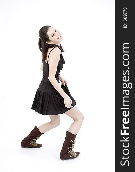 young brunette, in black short skirt and trendy fur boots, dancing on a white studio background. young brunette, in black short skirt and trendy fur boots, dancing on a white studio background