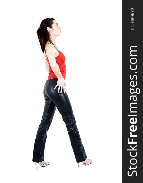 Young pretty brunette poses with attitude in the studio, dressed casual-rock, with a light red top and black leather pants, over a white background. Young pretty brunette poses with attitude in the studio, dressed casual-rock, with a light red top and black leather pants, over a white background