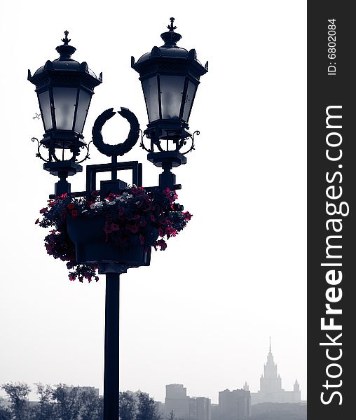 Street lantern with flowers and building on the background