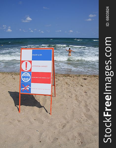 Sign Attention! Danger on the beach and man in the water. Sign Attention! Danger on the beach and man in the water.