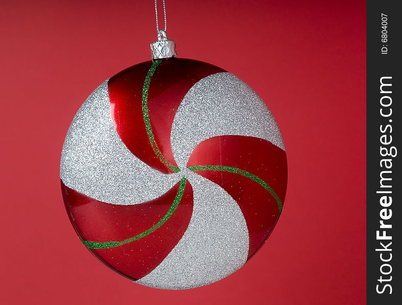 Glittery circle shape Christmas ornament against red background. Glittery circle shape Christmas ornament against red background