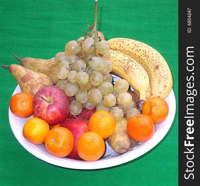 Fresh fruit white plate over green background