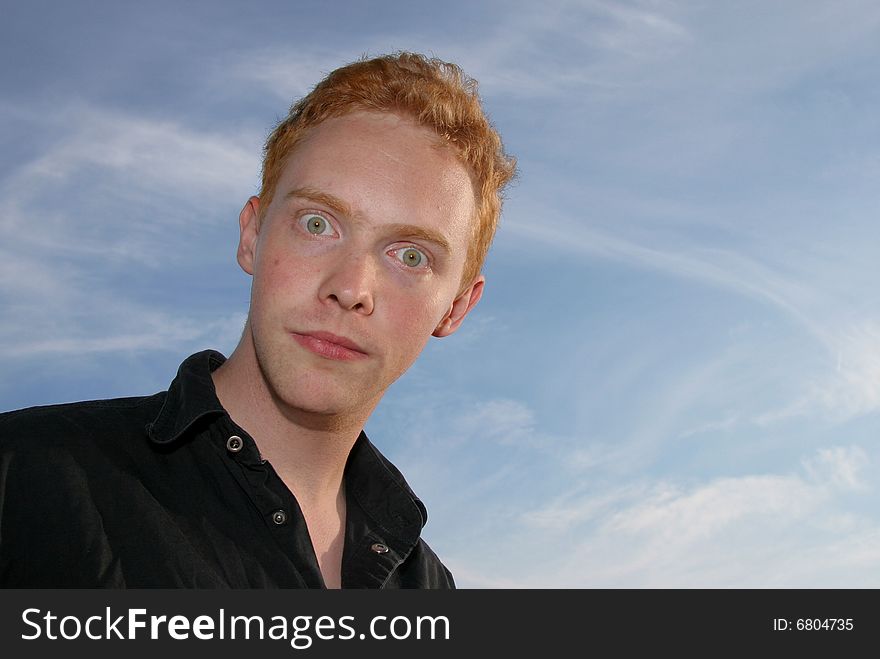 Wide-eyed young man against blue sky