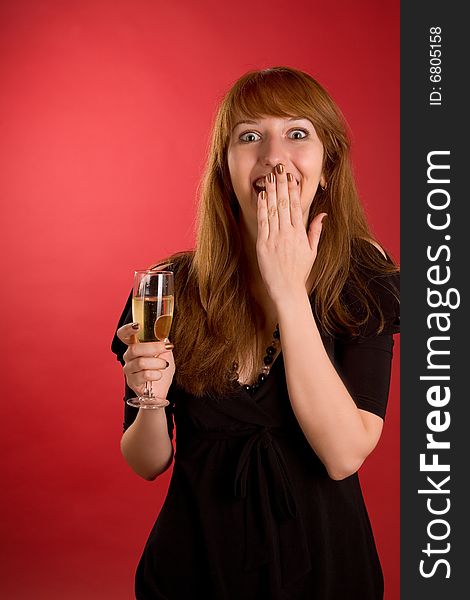 Surprised girl with champagne glass isolated on red background