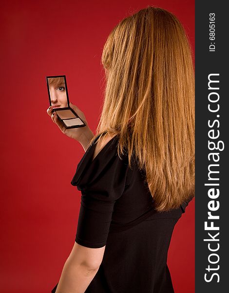 Beautiful girl looking in mirror, face in reflection, focus on hair