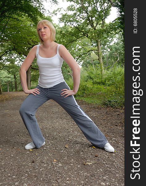 Cute blond girl outdoors doing stretching exercises. Cute blond girl outdoors doing stretching exercises