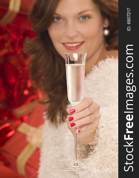 Beautiful woman toasting with a champagne glass in front of pile of gifts. Beautiful woman toasting with a champagne glass in front of pile of gifts