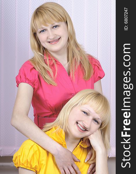 Two beautiful blond sisters together looking at camera