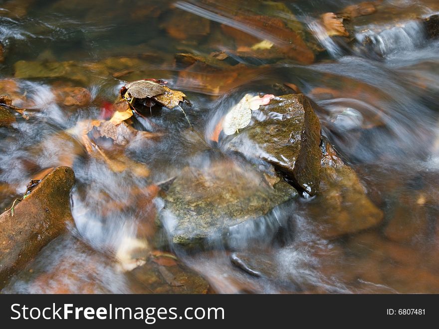 Water flowing over rocks with autumn leaves. Water flowing over rocks with autumn leaves