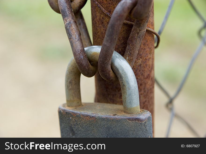 Padlock and chains on the rusty gate